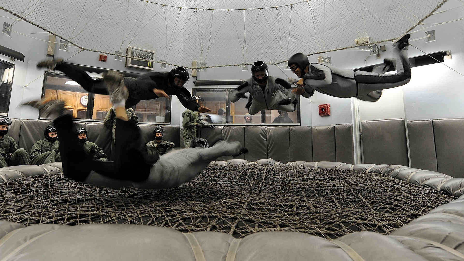 Hier ist eine Gruppe beim Indoor-Bodyflying zu sehen. Es werden Flugfiguren unter Anleitung eines Trainers ausprobiert.
