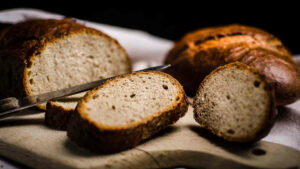Du riechst förmlich den Duft des Brots. Es wurde gerade selbst gebacken und liegt nun frisch angeschnitten auf einem Brett. Das Brotmesser befindet sich noch daneben.
