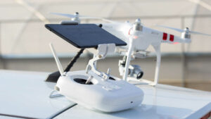 Wir sehen die Mindest-Ausstattung für FPV-Flüge – First Person View Flüge. Im Vordergrund liegt die Fernbedienung mit dem aufgesteckten Tablet als Monitor. Dahinter steht der Quadrocopter mit der Kamera.