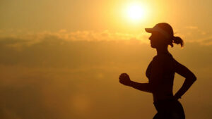 Von einer Joggerin ist nur eine Silhouette zu sehen, da im Hintergrund die Abendsonne scheint.