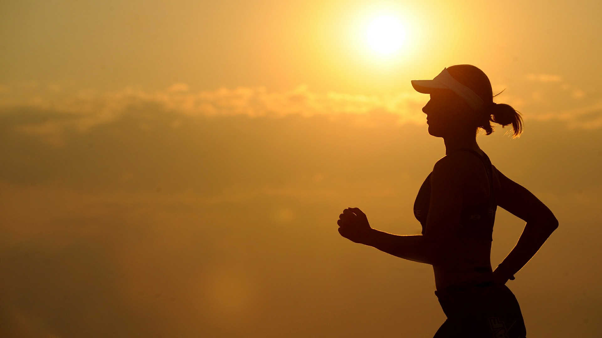 Von einer Joggerin ist nur eine Silhouette zu sehen, da im Hintergrund die Abendsonne scheint.
