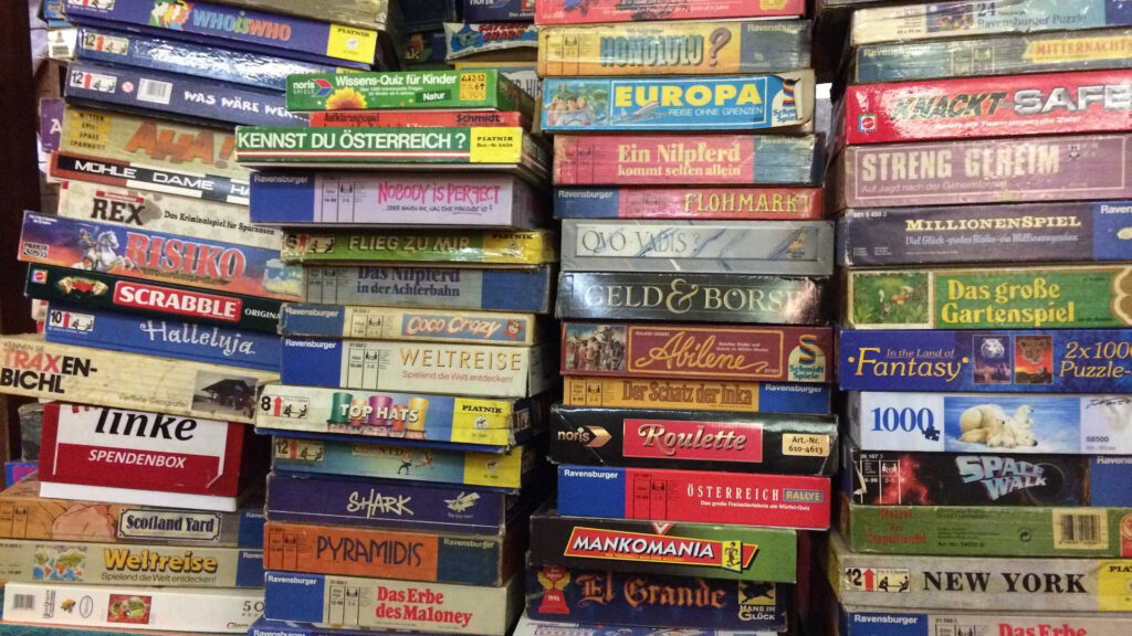Brettspiele - Wir sehen eine scheinbar unendliche Anzahl von Kartons mit Spielen über- und nebeneinander gestapelt.
