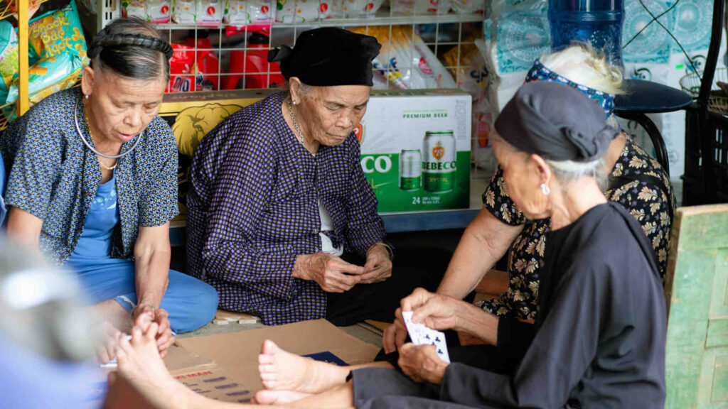 Vier Frauen spielen in der Ecke eines Marktes in Hà Giang, Vietnam Karten.