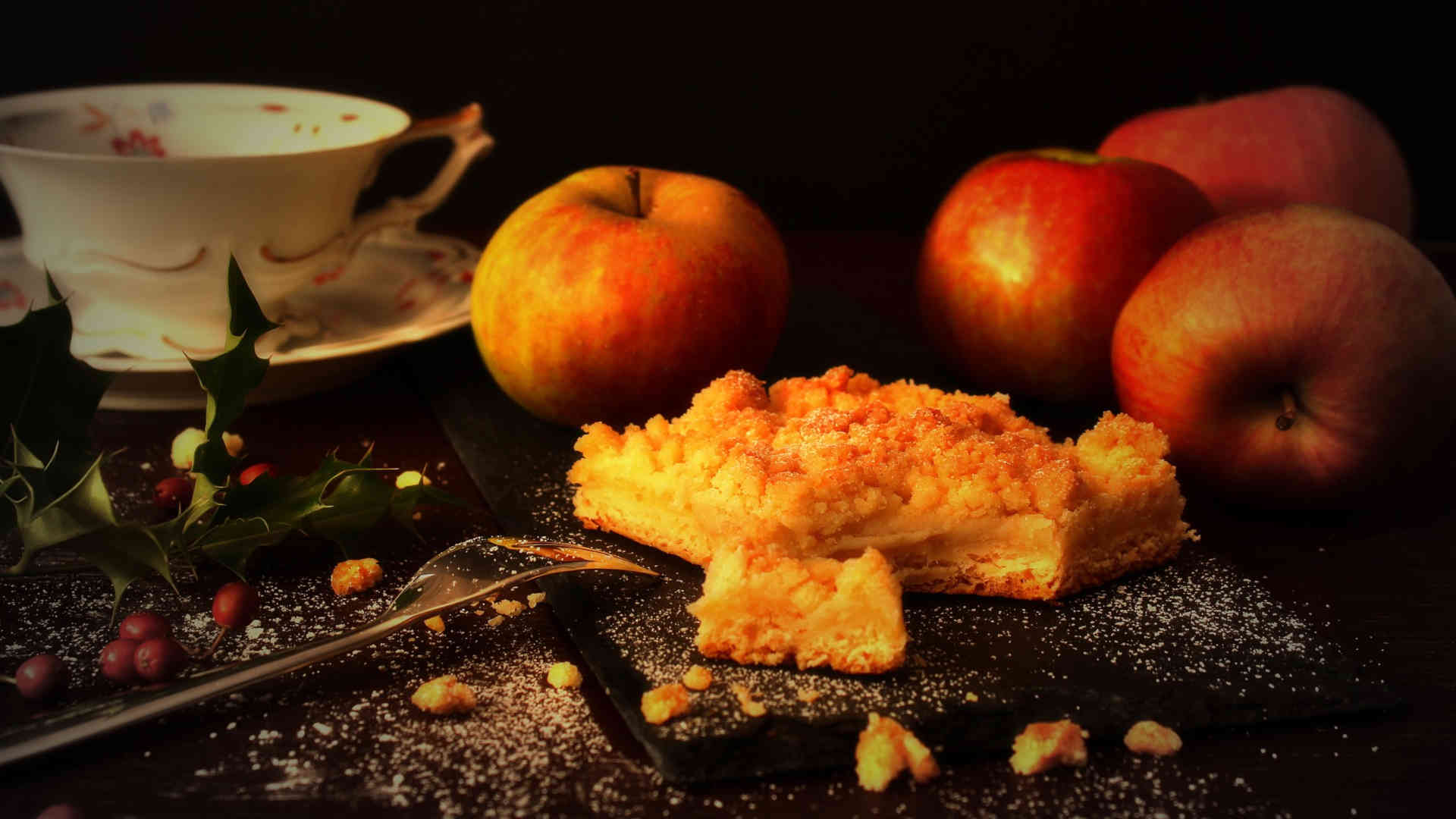 Backen – Ein Apfelkuchen, halb aufgegessen, und eine Tasse Kaffee. Dazu ein paar frische Äpfel.