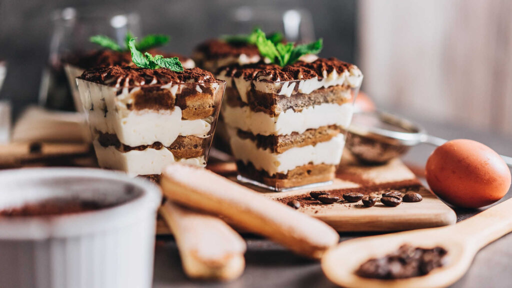 Backen – Tiramisu in Gläsern angerichtet, schön dekoriert und mit einer Tasse Kaffee ergänzt.