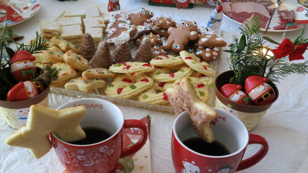 Backen von Keksen in der Adventszeit. Diese werden auf einem Teller präsentiert, ergänzt mit zwei Tassen Kaffee.