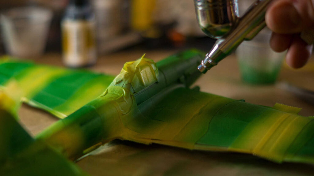 Airbrush – Mithilfe von Airbrush wird hier ein Modellflugzeug grün lackiert.