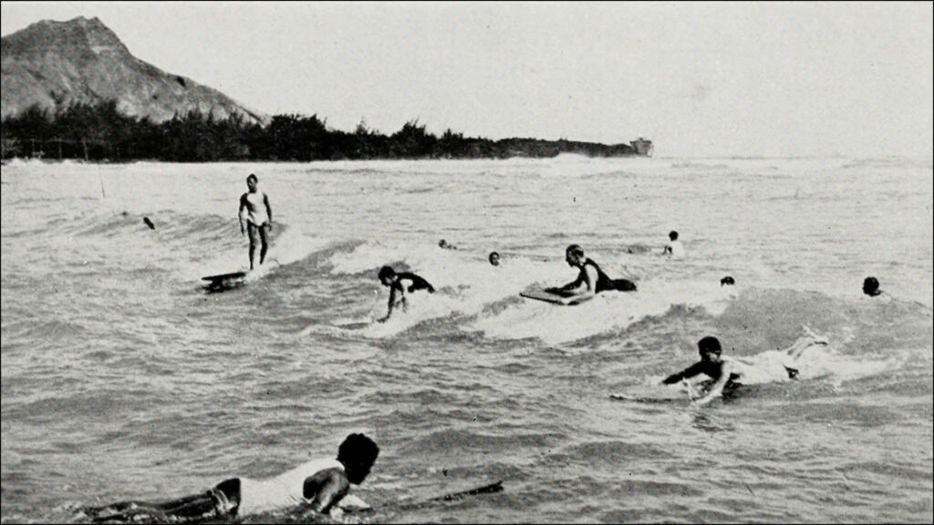 Surfen 1922: Hawaiianer genießen das Schwimmen am Waikiki Beach in Honolulu. Mit Surfbrettern und Auslegerkanus reiten sie auf den wildesten Wellen.