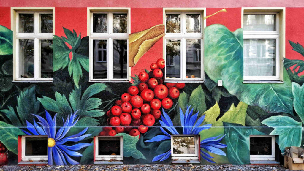 Graffiti – Auf einer roten Hauswand wurden mit Graffiti Früchte und Pflanzen gemalt.