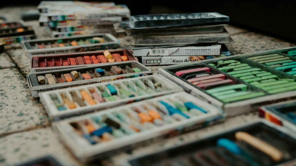 Pastellmalerei – Auf diesem Arbeitstisch ist Pastellkreide in vielen verschiedenen Varianten zu sehen.