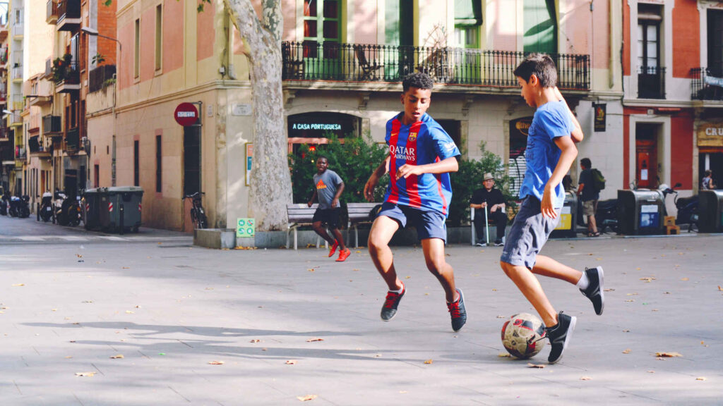 Fußball – Zwei Jungen spielen auf der Straße Fußball.